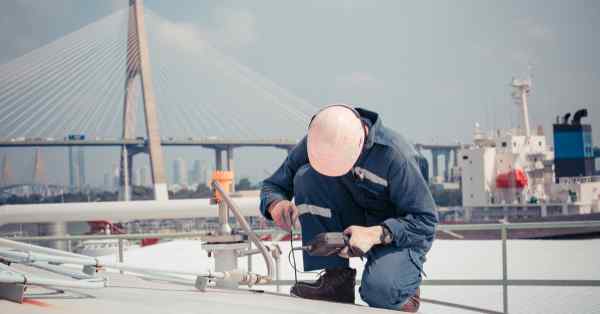 man kneeling on the roof taking measurments