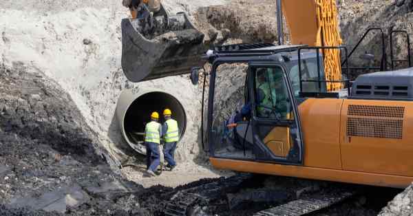 men constructing a pipeline with an excavator